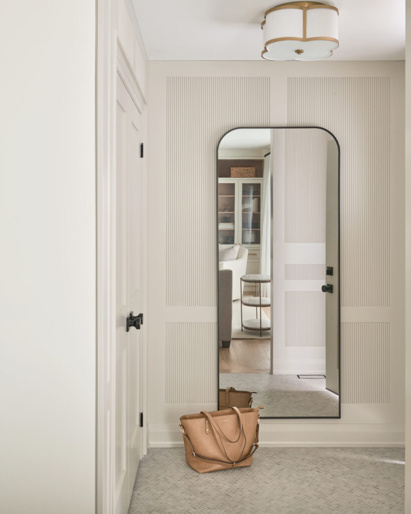 Renovated entryway featuring reeded wall paneling, herringbone tile flooring, and large arched mirror. Suburban Toronto home renovation by Erin Interiors, Durham Region Interior Designer.