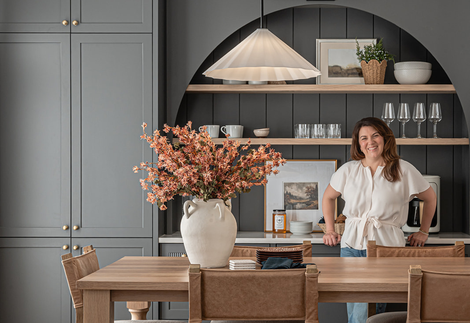 Transitional kitchen with arched coffee bar in Benjamin Moore Overcoat and integrated island dining table with turned legs.