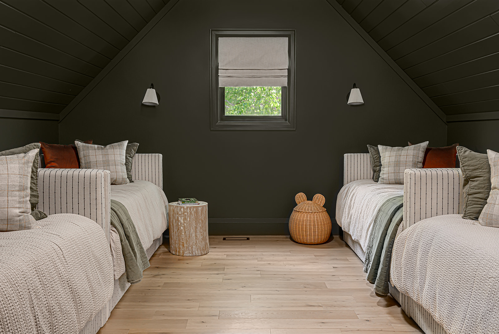 Kids' loft in an Ontario cottage with a dark green shiplap vaulted ceiling, two striped upholstered twin beds, wall sconces, and a small window.